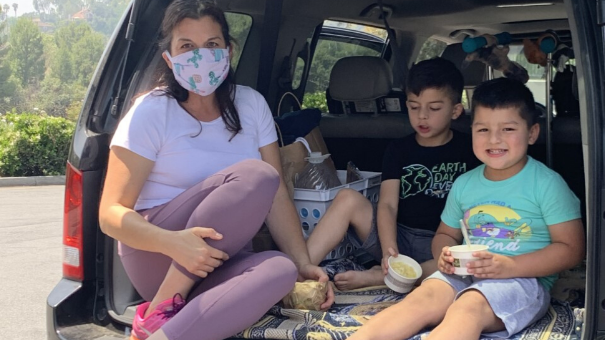 A mom wearing a face mask with two sons eating lunch sitting on the car trunk during the safer-at-home order in Altadena