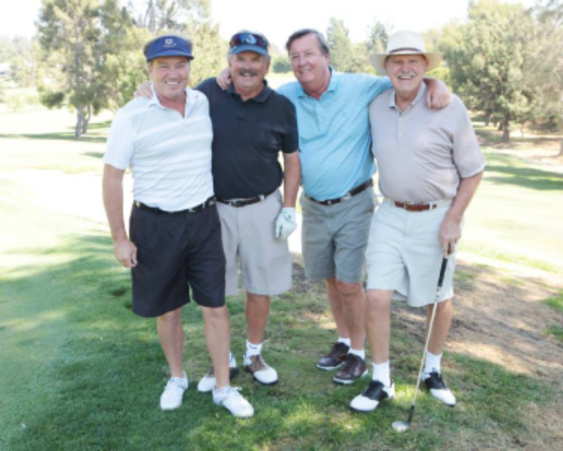 Four friends posing on a golf course