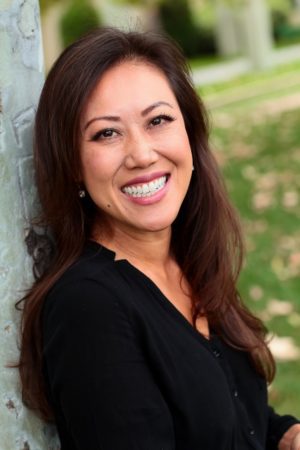 Smiling woman outdoors leaning on a tree