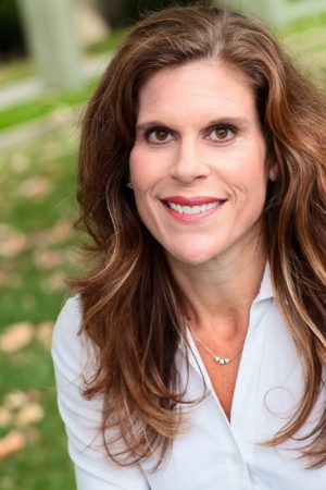 Woman in white shirt sitting on grass.